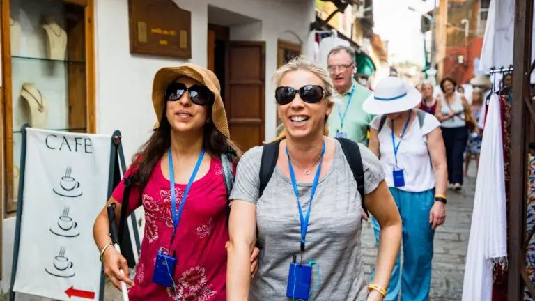 Smiling tour group with lanyards walking past a café